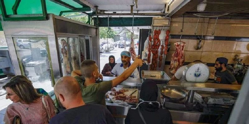Sejumlah orang menunggu pesanan mereka di toko daging di kota pelabuhan Tripoli di Libanon utara pada 28 Juli 2020/AFP

