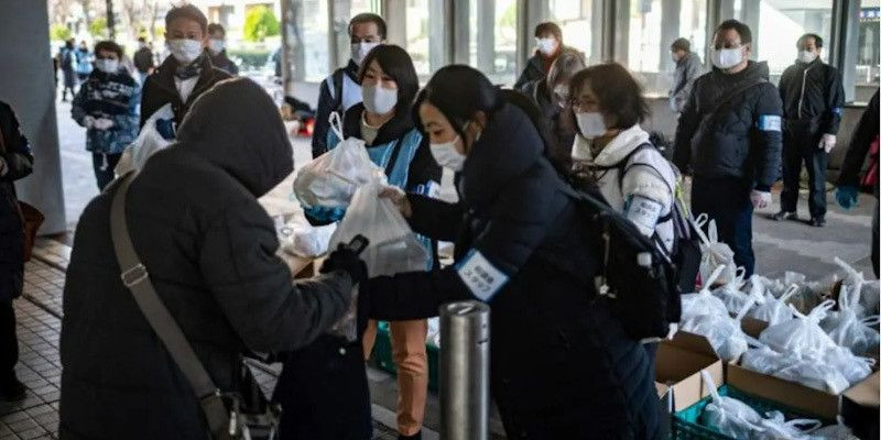 Sejumlah orang membagikan paket bantuan di tengah pandemi Covid-19 di Jepang/AFP