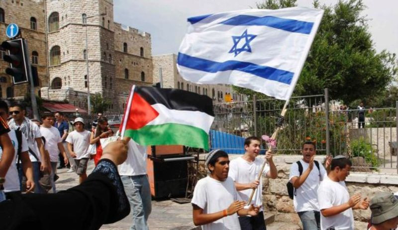 Sejumlah orang membawa bendera Palestina dan Israel, berharap pertikaian segera usai/Reuters