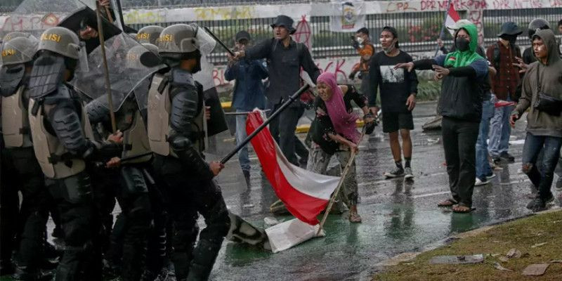 Seorang ibu memegang bendera Merah Putih di antara demonstran dan aparat di Jakarta. (B-Universe Photo)